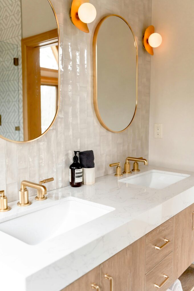 Stylish bathroom interior featuring double sinks and gold fixtures with modern mirrors.